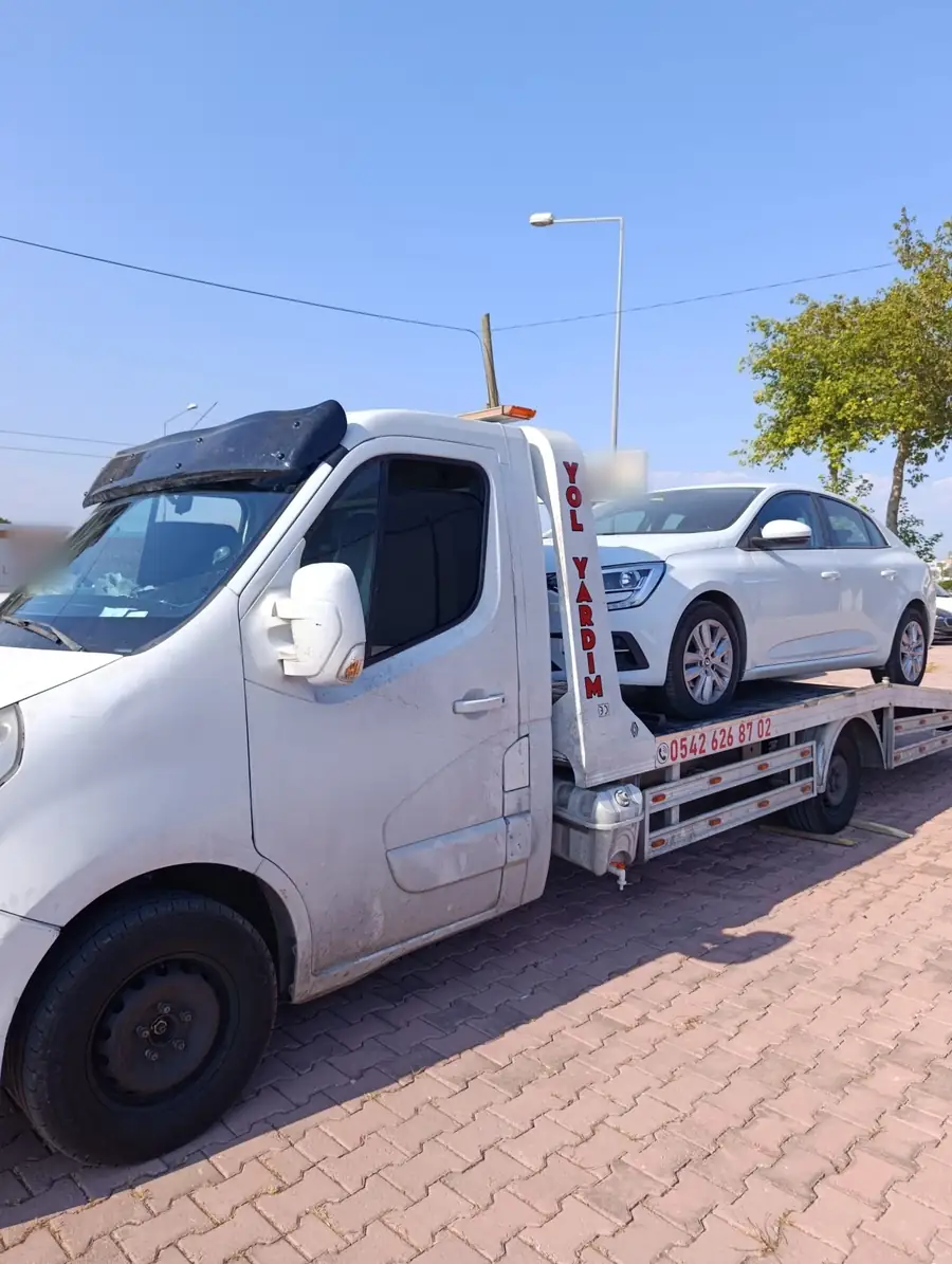 Gündüz, platformlu oto çekici beyaz bir sedan otomobili kayar platformunda taşıyor